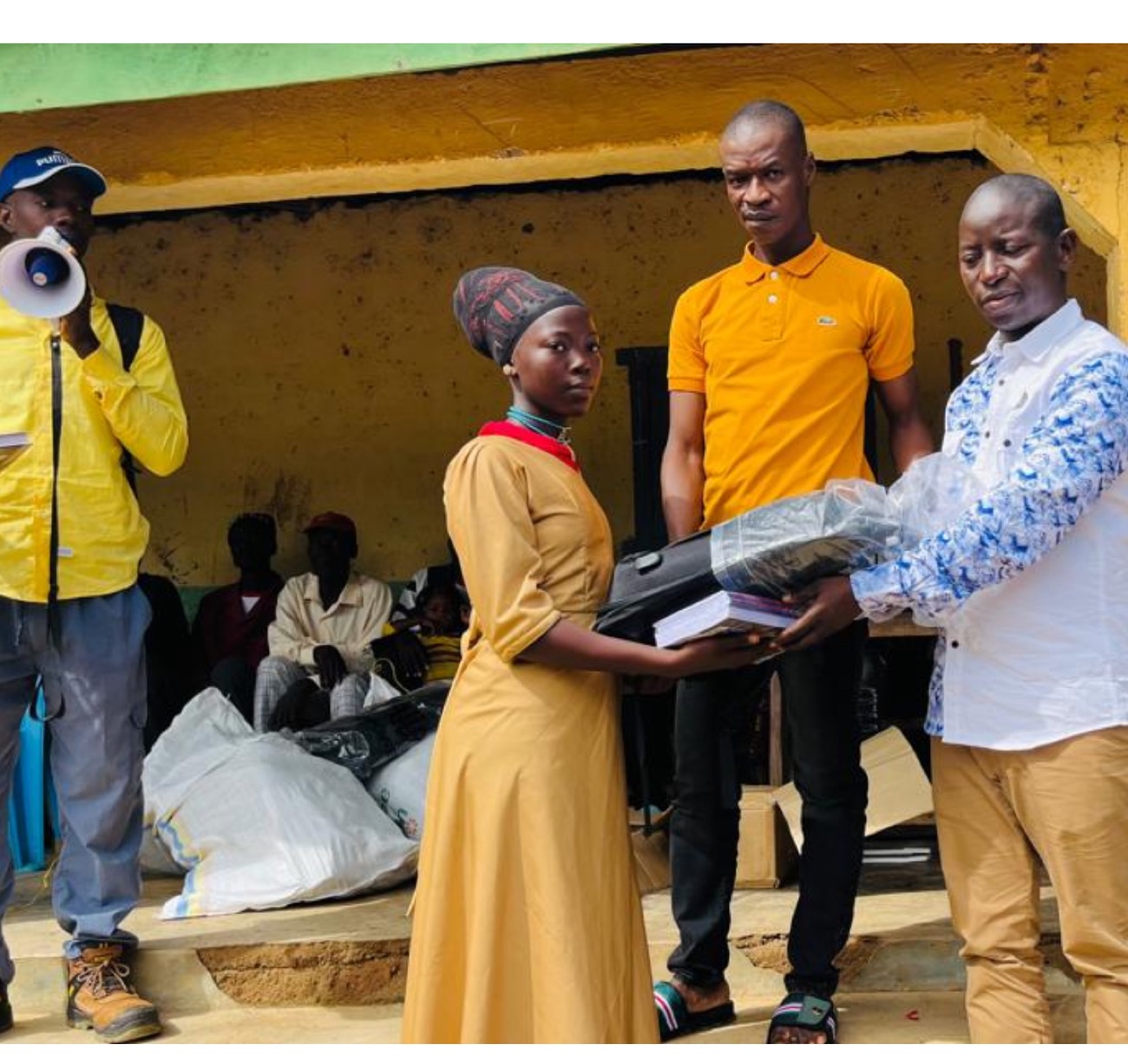 A student receiving books and resources from a community official at a Trust distribution event