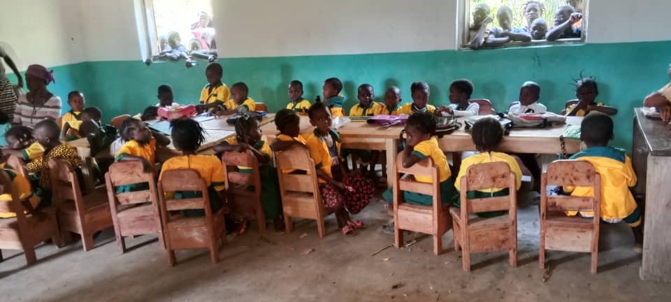 Children learning at their desks inside a Tolno Education Trust classroom in Millimou