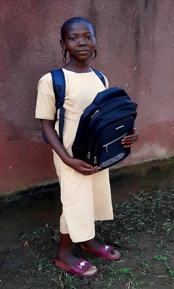Sia Fanta Yombouno standing with her new school backpack in Millimou