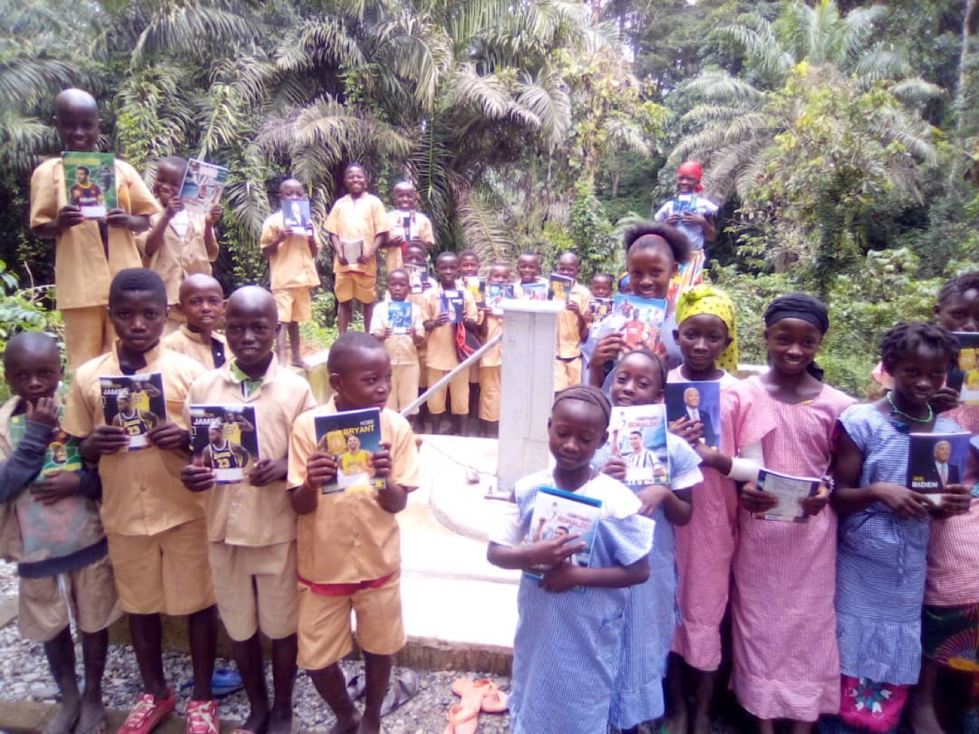 Children in Millimou holding books they have received from the Trust