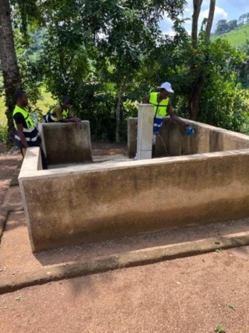 A newly built concrete water reservoir in the community, with Trust workers alongside